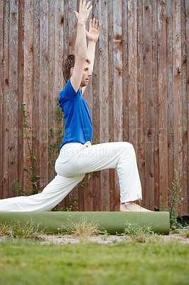 Buy stock photo Shot of a handsome man doing yoga in his backyard