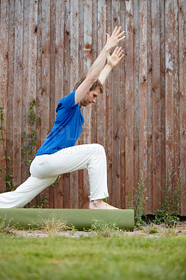 Buy stock photo Shot of a handsome man doing yoga in his backyard