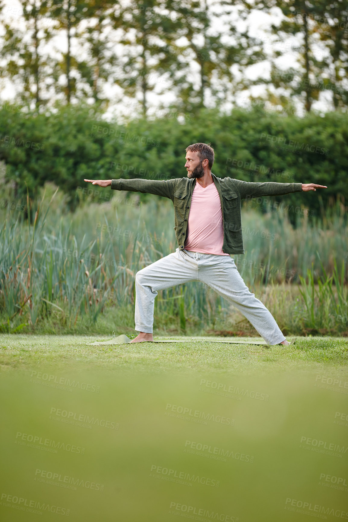 Buy stock photo Shot of a handsome mature man doing yoga at a park