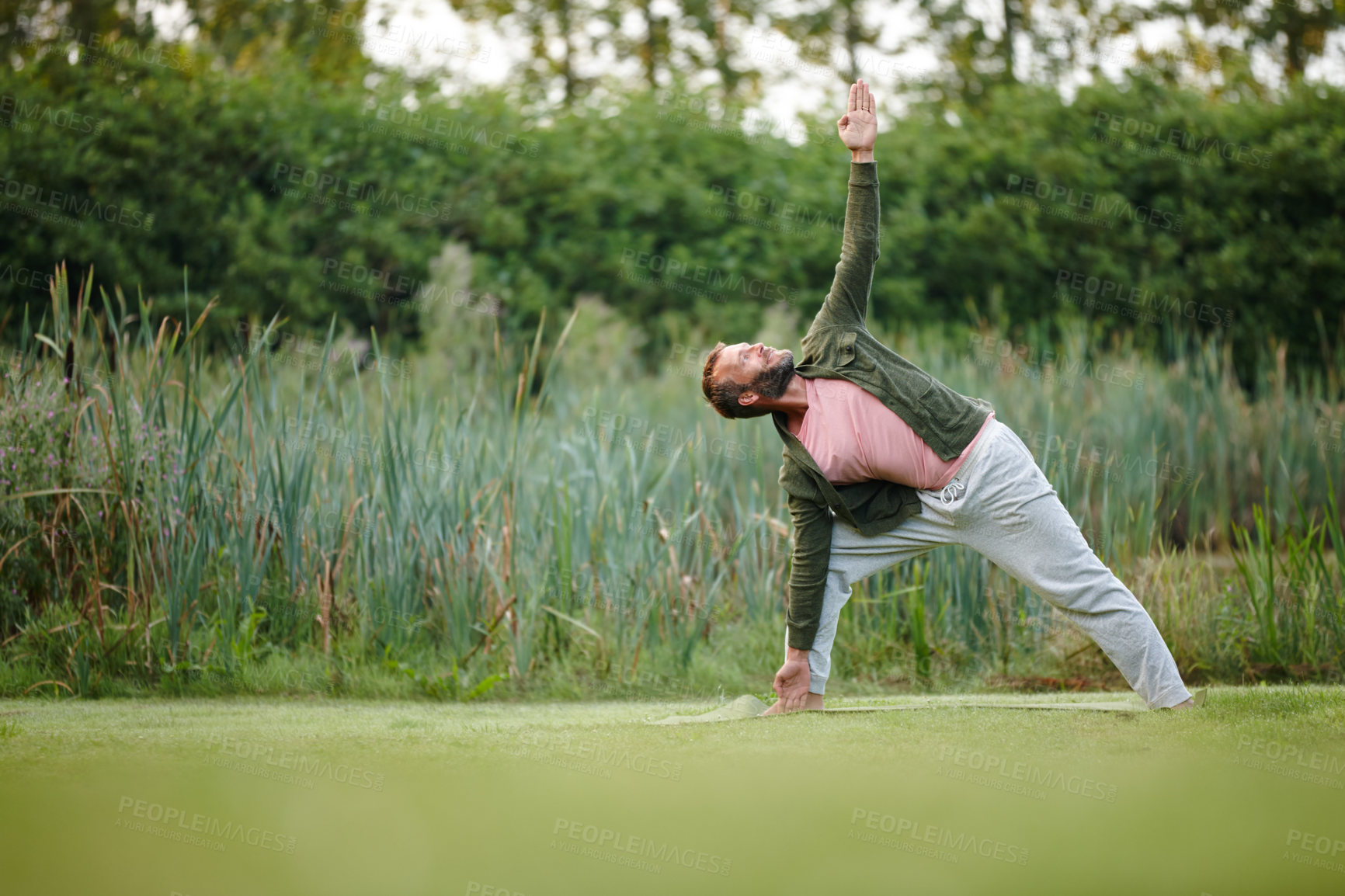 Buy stock photo Shot of a handsome mature man doing yoga at a park