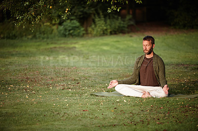 Buy stock photo Shot of a handsome mature man meditating in the lotus position in the outdoors