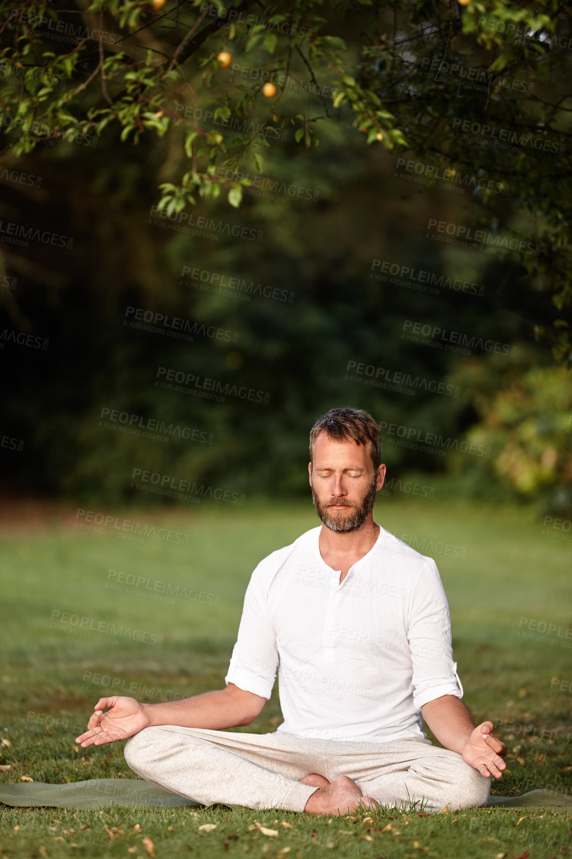 Buy stock photo Shot of a handsome mature man sitting in the lotus position with his eyes closed