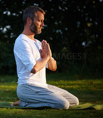 Buy stock photo Shot of a handsome mature man kneeling on his yoga mat with his hands in prayer position