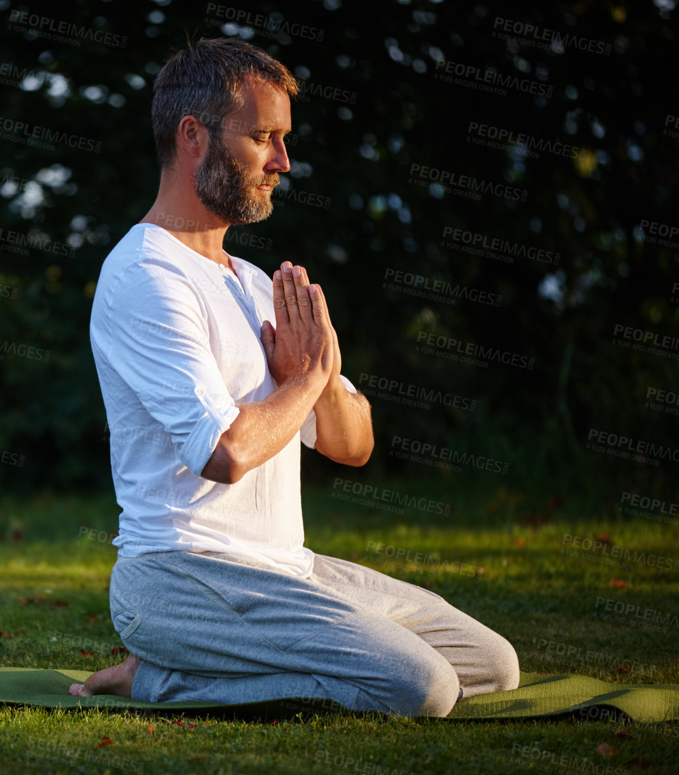 Buy stock photo Shot of a handsome mature man kneeling on his yoga mat with his hands in prayer position