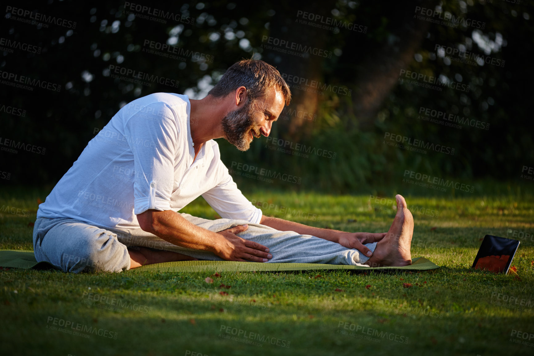 Buy stock photo Shot of a mature man looking at online instructions on his tablet while doing yoga