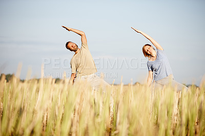 Buy stock photo Shot of a mature couple enjoying a yoga workout in a crop field