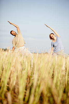 Buy stock photo Shot of a mature couple enjoying a yoga workout in a crop field