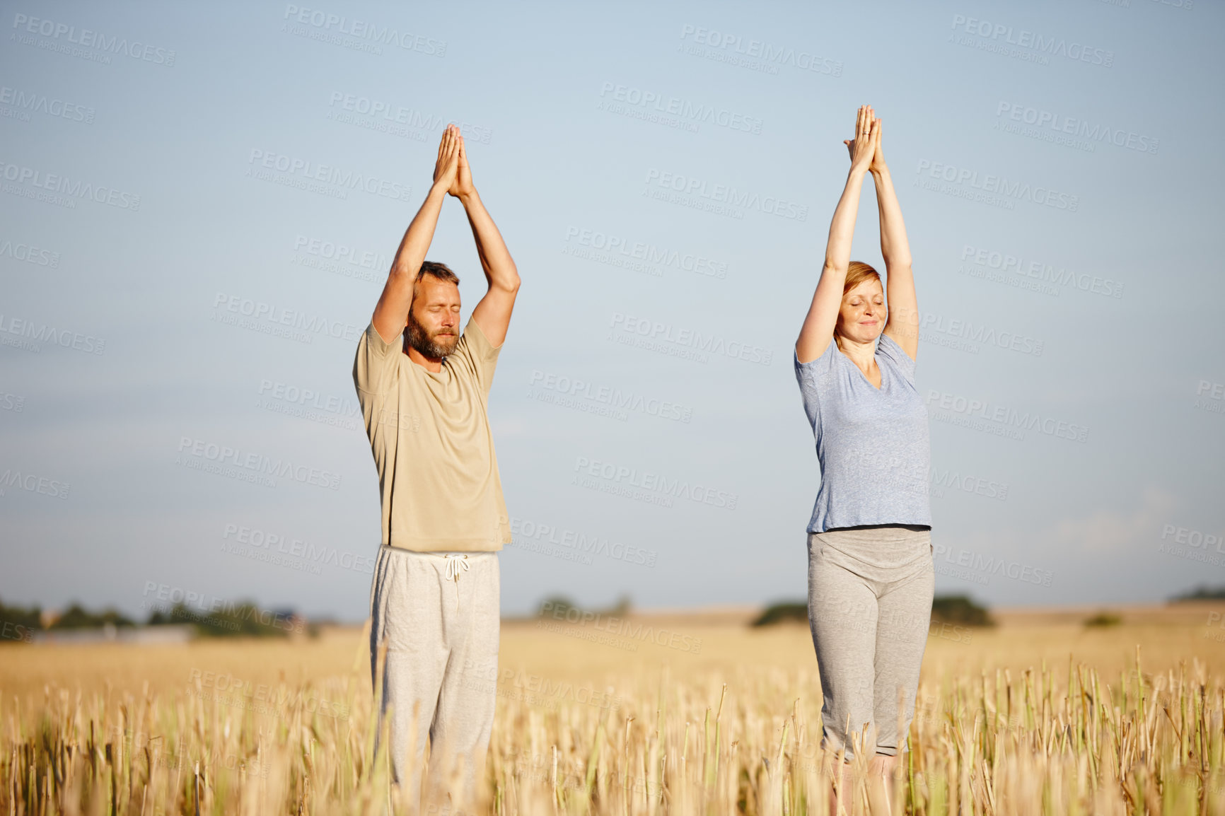 Buy stock photo Shot of a serene couple enjoying a yoga workout in a crop field