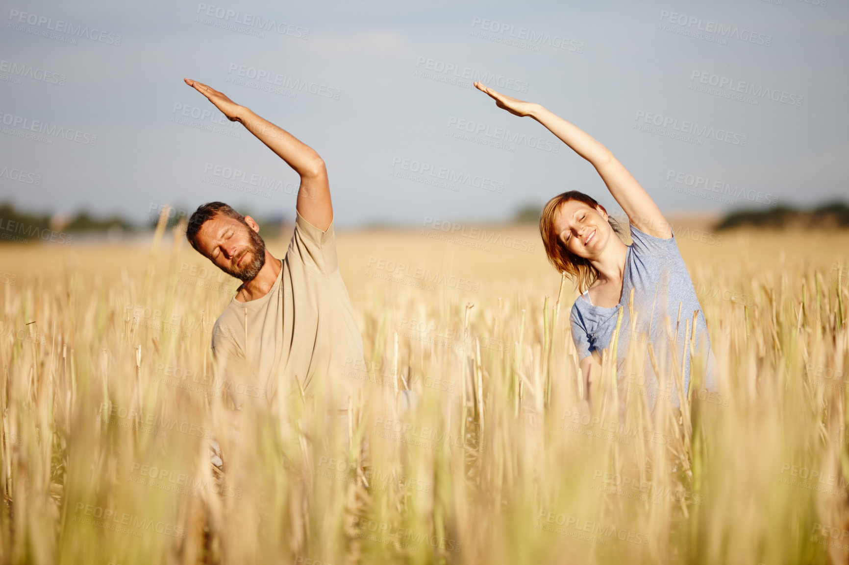 Buy stock photo Shot of a serene couple enjoying a yoga workout in a crop field