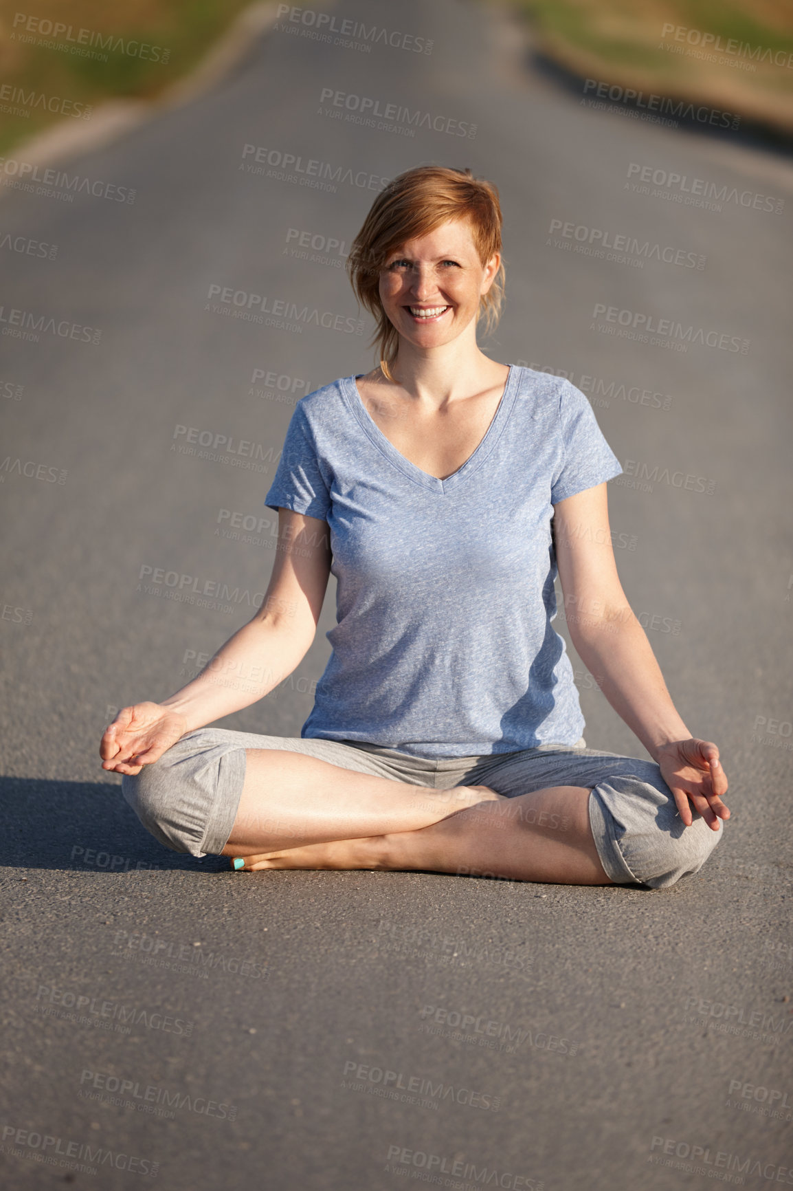 Buy stock photo Portrait of an attractive woman sitting in the lotus position on a country road