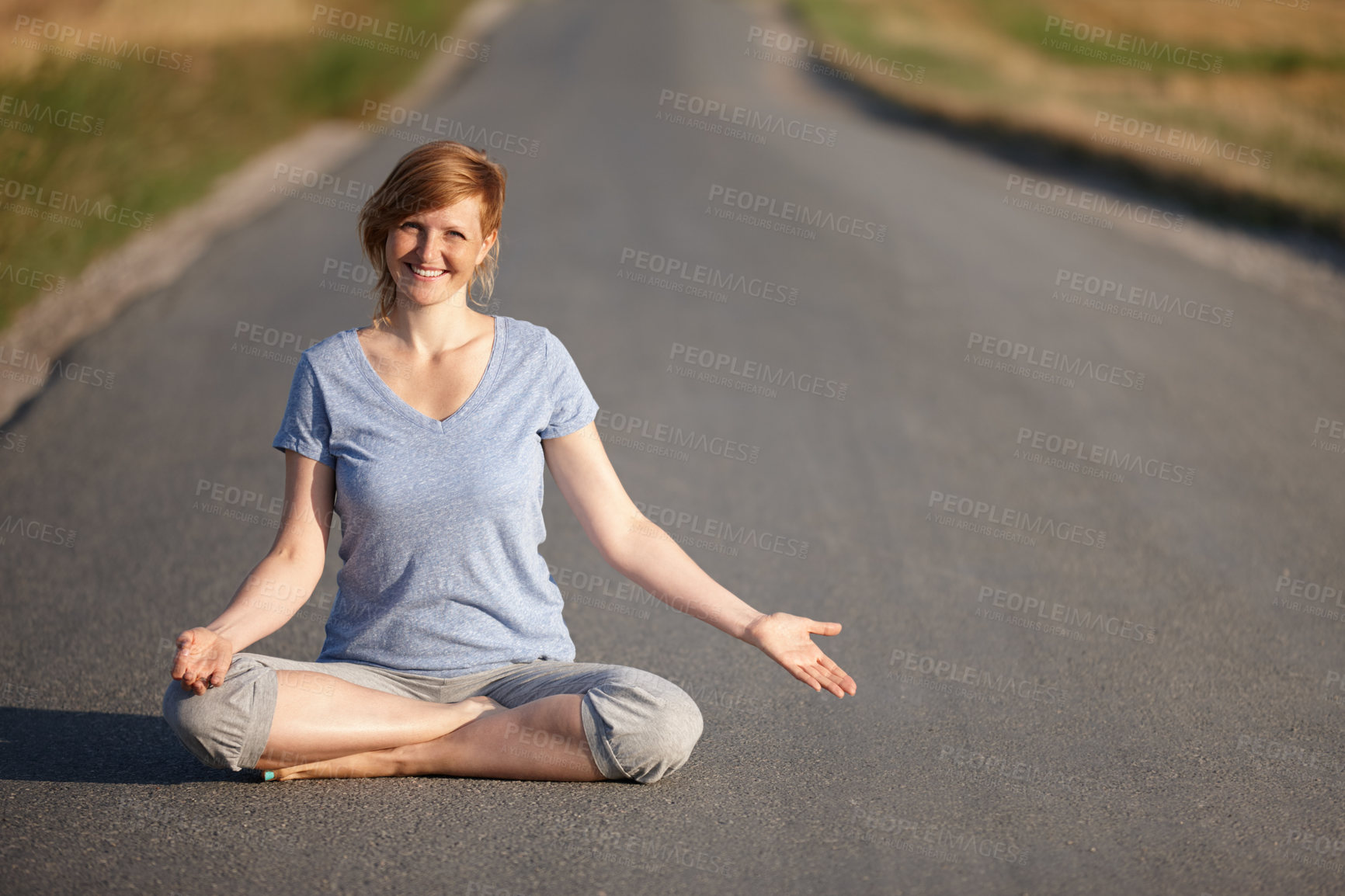 Buy stock photo Portrait of an attractive woman sitting in the lotus position on a country road