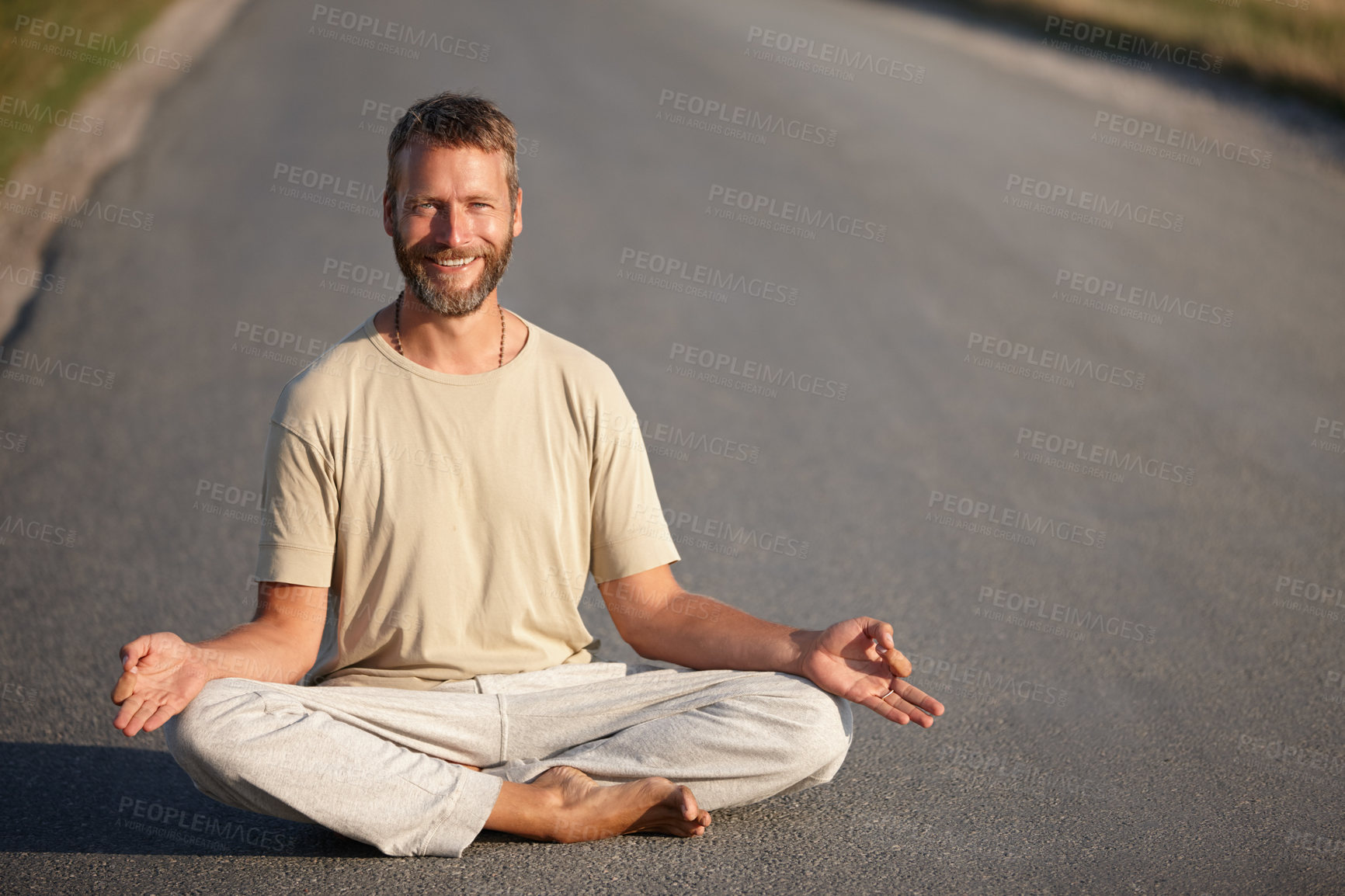 Buy stock photo Portrait of a handsome mature man sitting in the lotus position on a road