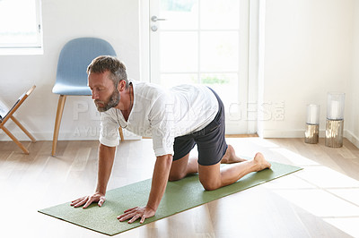 Buy stock photo Shot of a handsome mature man doing yoga at home