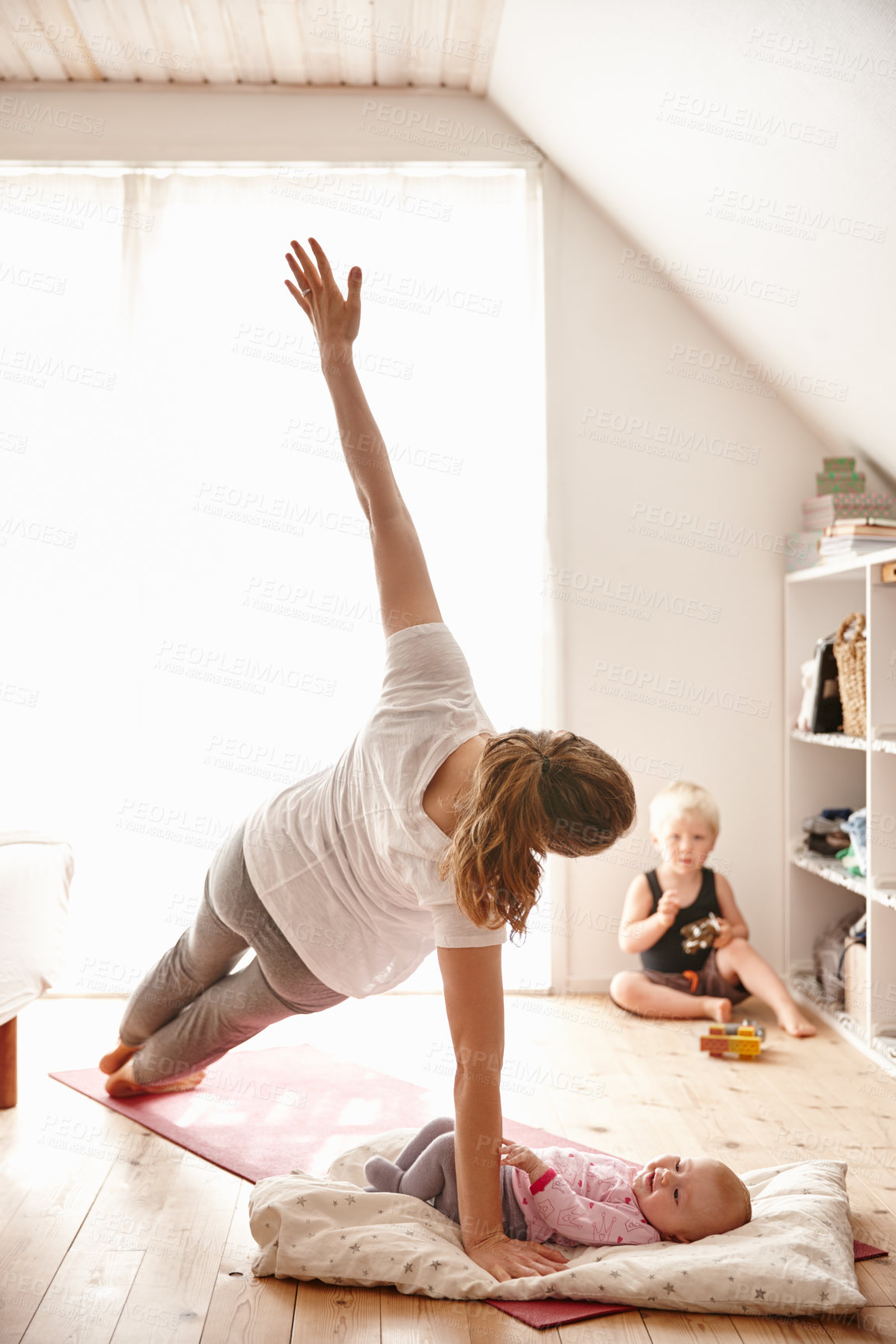 Buy stock photo Shot of an attractive young woman bonding with her children while doing yoga