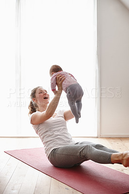 Buy stock photo Shot of an attractive young woman bonding with her baby girl while doing yoga