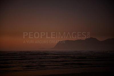 Buy stock photo Shot of ocean and distant mountains just before daybreak