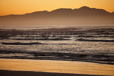 Buy stock photo Shot of a peaceful scene of ocean and distant mountains at dawn