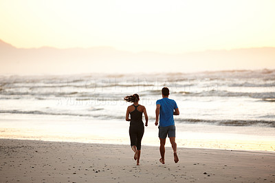 Buy stock photo Rearview of a couple enjoying a beach run at daybreak
