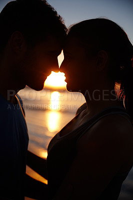 Buy stock photo Closeup image of a romantic couple silhouetted against the sunrise