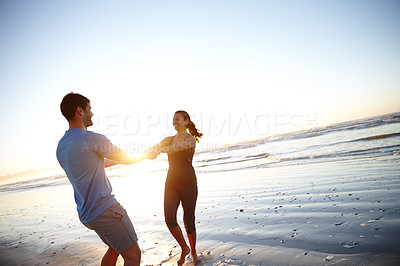 Buy stock photo Shot of a happy couple enjoying some time on the beach at sunrise