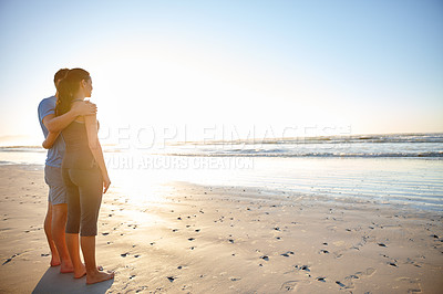 Buy stock photo Shot of a young couple looking out over the ocean on a beach at sunrise