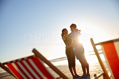 Buy stock photo Shot of a happy young couple on a beach with deck chairs