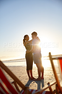 Buy stock photo Shot of a happy young couple on a beach with deck chairs