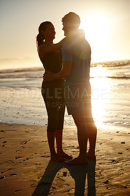 Buy stock photo Shot of a hugging couple silhouetted against a sunrise over the sea