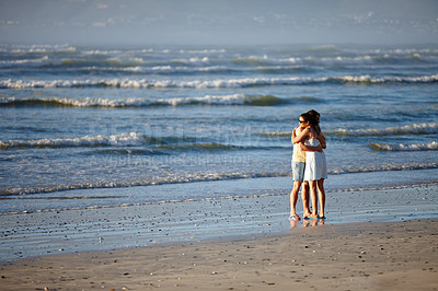 Buy stock photo Shot of a couple hugging at the tideline on a beach