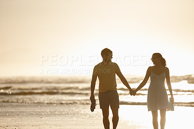 Buy stock photo Shot of a happy couple enjoying walking together on the beach at sunrise