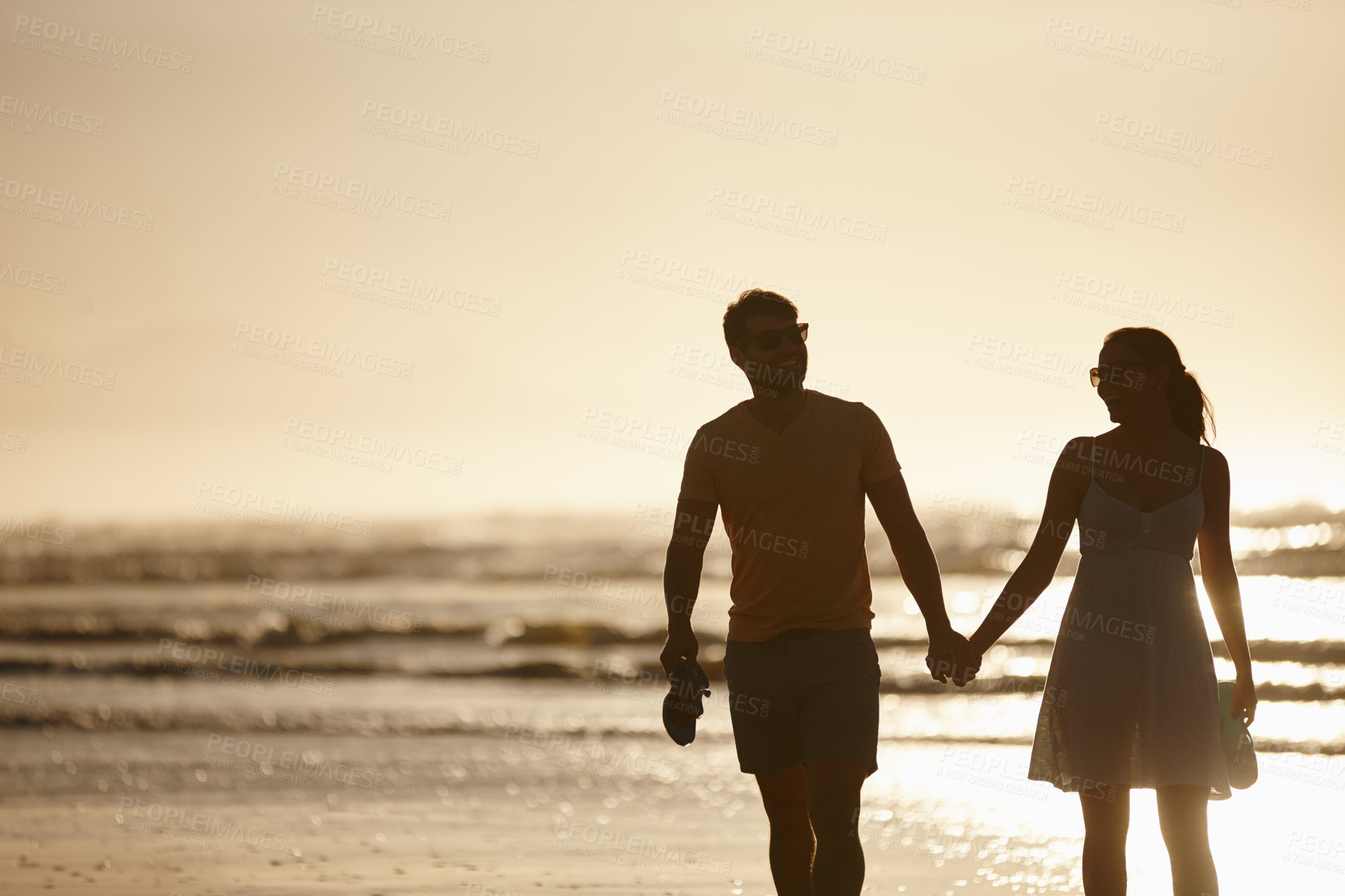 Buy stock photo Silhouetted image of a couple holding hands in front of the sea