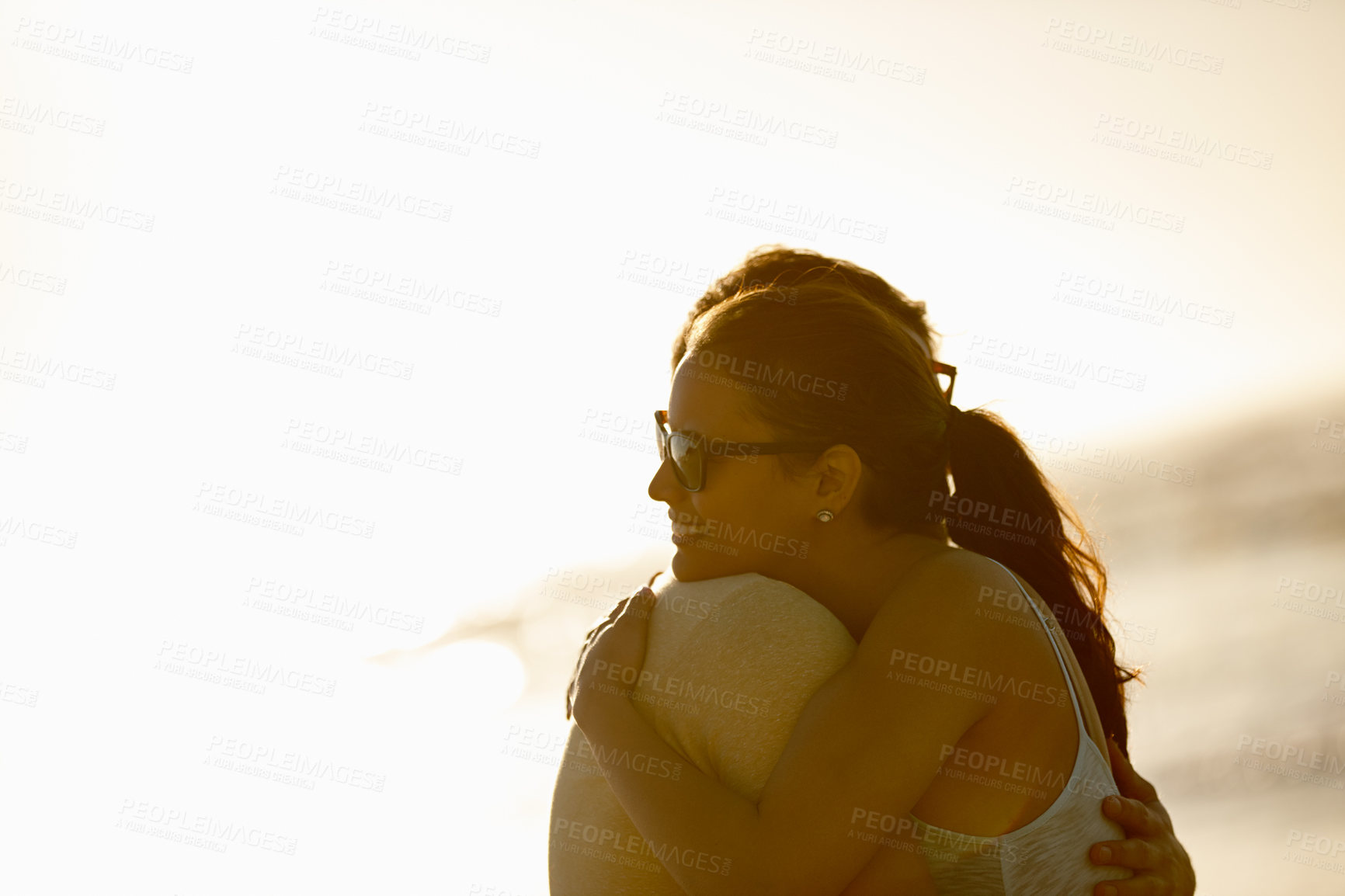 Buy stock photo Shot of a happy young couple hugging outdoors with a bright sky behind