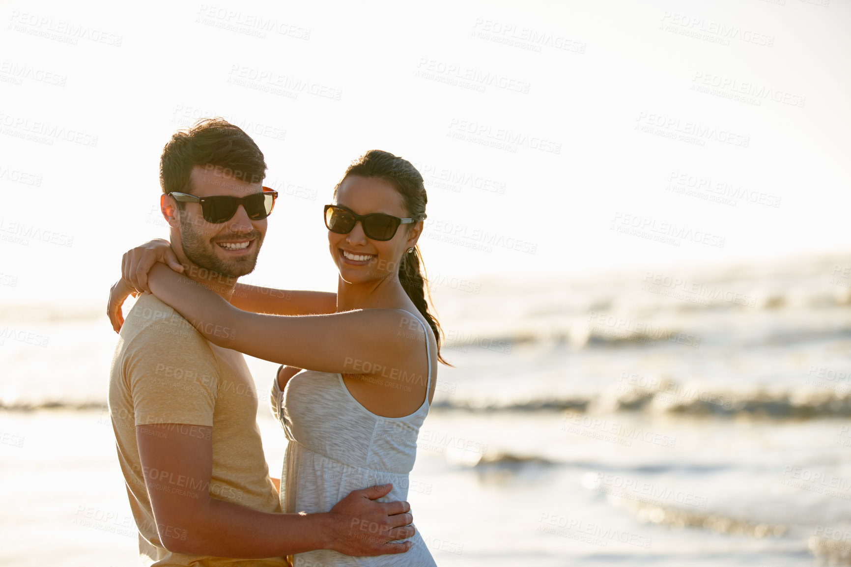 Buy stock photo Shot of a romantic young couple smiling with ocean in the background