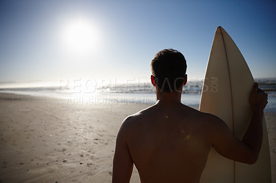 Buy stock photo Rearview shot of a young male surfer looking out at the beach and distant waves