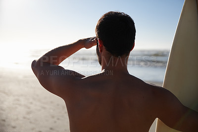 Buy stock photo Rearview shot of a young male surfer looking out at the beach and distant waves