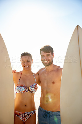 Buy stock photo Portrait shot of a happy young couple smiling with their surfboards at the beach