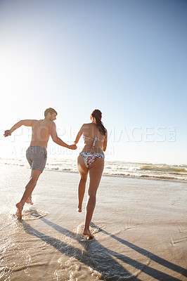 Buy stock photo Happy couple, running or holding hands with blue sky on beach for fun summer, holiday or weekend in nature. Back view, man and woman with smile for playful vacation or bonding on ocean coast or shore