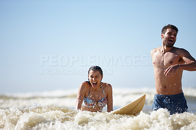 Buy stock photo Shot of a laughing young woman being given a surfing lesson