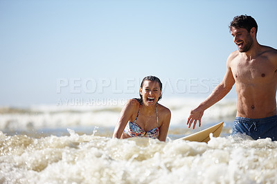 Buy stock photo Shot of a laughing young woman being given a surfing lesson