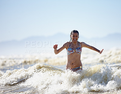 Buy stock photo Shot of a happy young woman running out of the surf