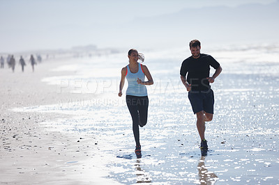 Buy stock photo Shot of a young couple running along a beach together 