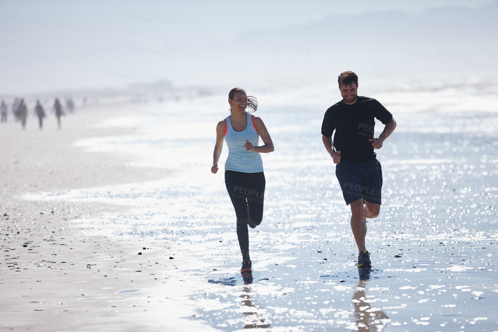 Buy stock photo Shot of a young couple running along a beach together 