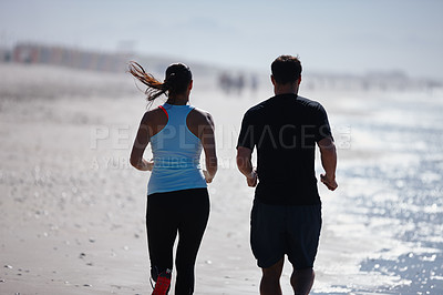 Buy stock photo Cropped rearview shot of a couple enjoying a beach run together