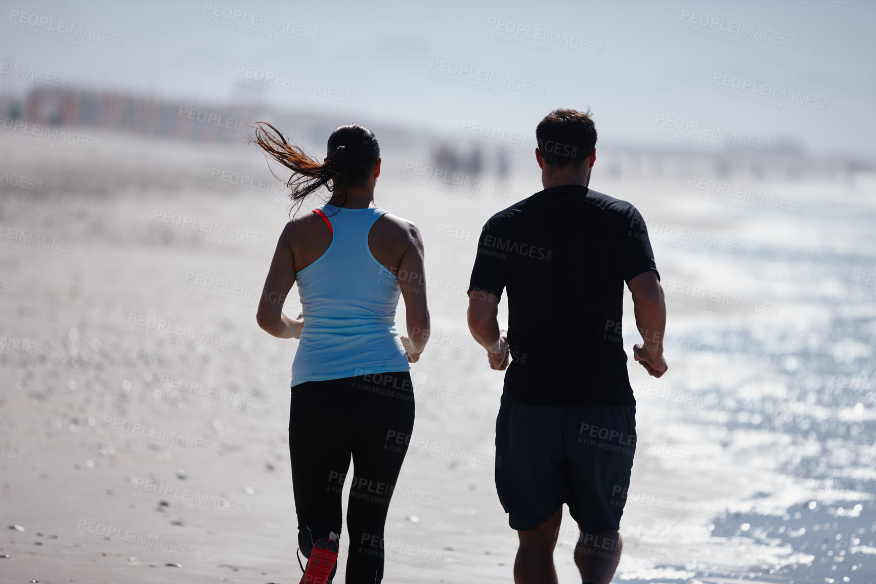 Buy stock photo Cropped rearview shot of a couple enjoying a beach run together