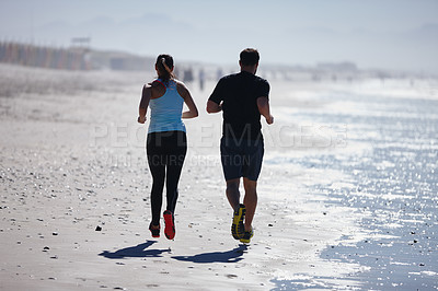 Buy stock photo Rearview shot of a couple enjoying a beach run together