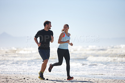 Buy stock photo Full length shot of a young couple running along a beach together