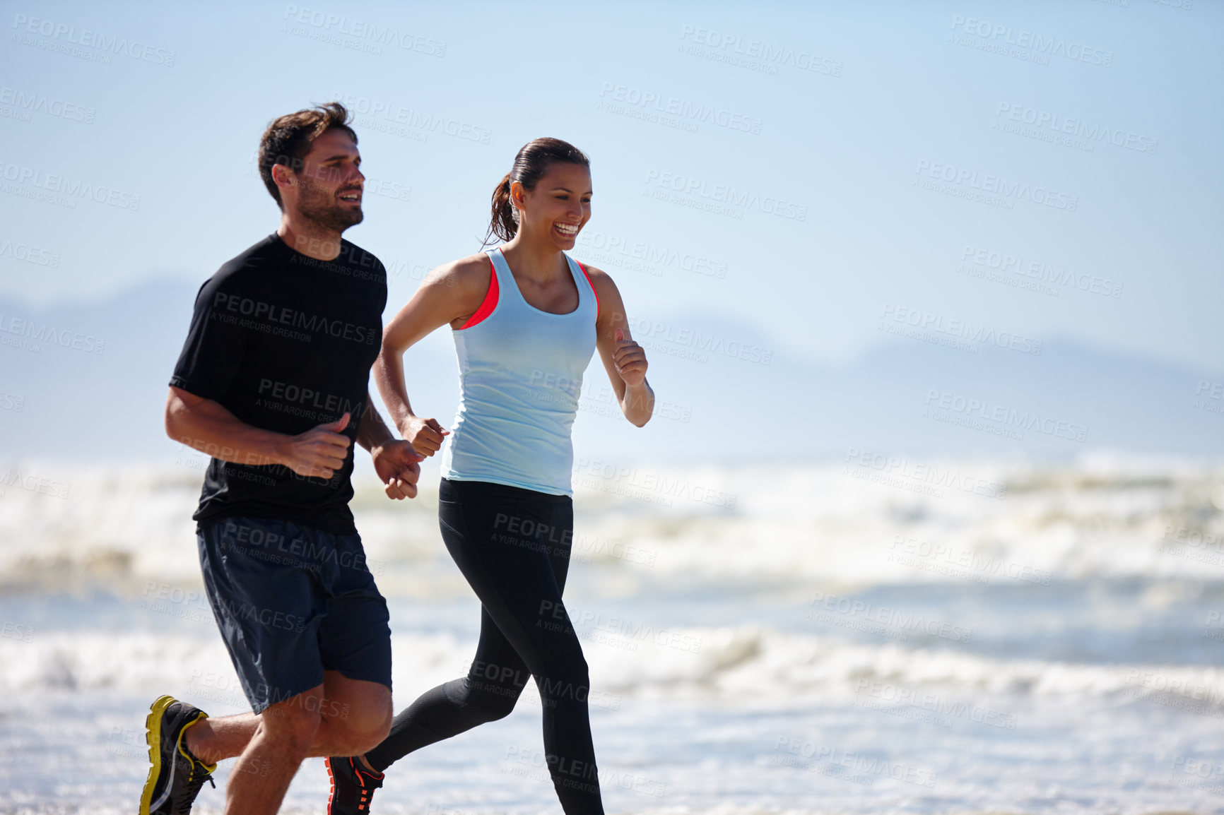 Buy stock photo Cropped shot of a young couple running along a beach together