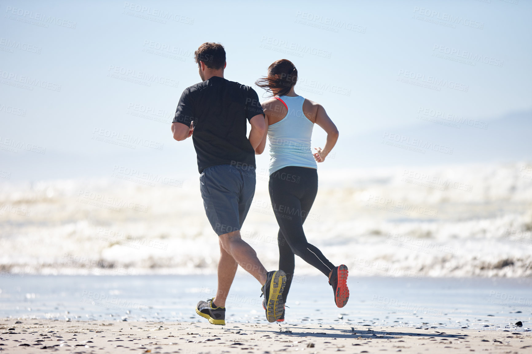 Buy stock photo Rearview shot of a couple enjoying a beach run together