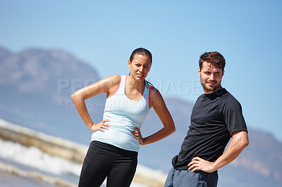 Buy stock photo Shot of a tired young couple taking a break during a beach run