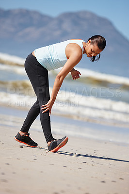 Buy stock photo Full length shot of a young woman warming up for a beach run